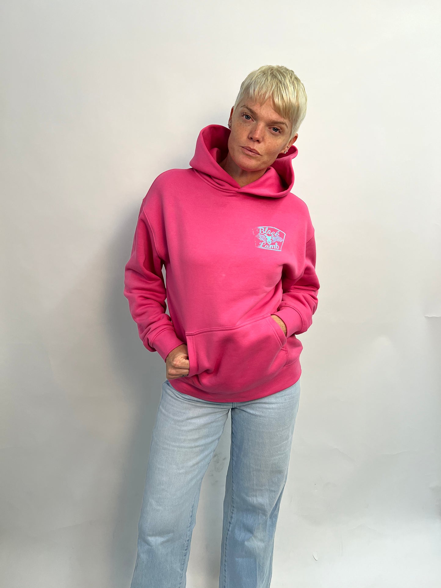 Person wearing a bright pink hoodie with a logo on a plain background